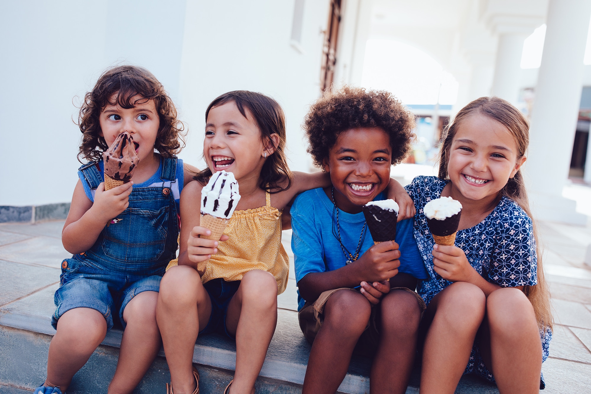 Multi-ethnic best friends children eating ice-cream and having fun on summer holidays